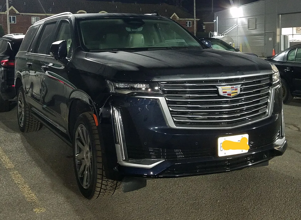 A dark blue Cadillac Escalade ESV from the same generation as the 2022 Escalade, parked in a lot at night